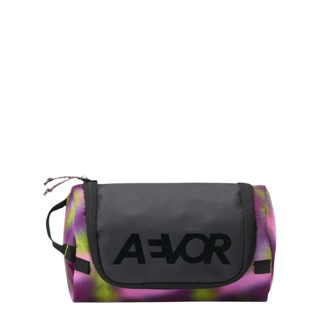 Lieblingstasche Aevor Wash Pack toiletry bag in a vibrant purple and green tie-dye pattern with black logo detail