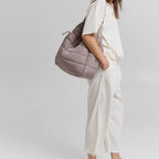 Model wearing a Lieblingstasche Alltime Buddy quilted taupe shoulder bag with a casual cream linen outfit