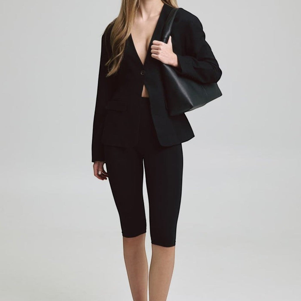 Lieblingstasche Alltime Lover M black leather shoulder bag worn by a model in a black blazer and cycling shorts