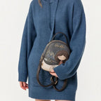 Lieblingstasche Anekke backpack with whimsical girl illustration and floral details held by a woman in a blue sweater