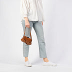 Lieblingstasche aunts & uncles Mrs. Whoopie Pie brown leather crossbody bag held by a woman in jeans and white shirt