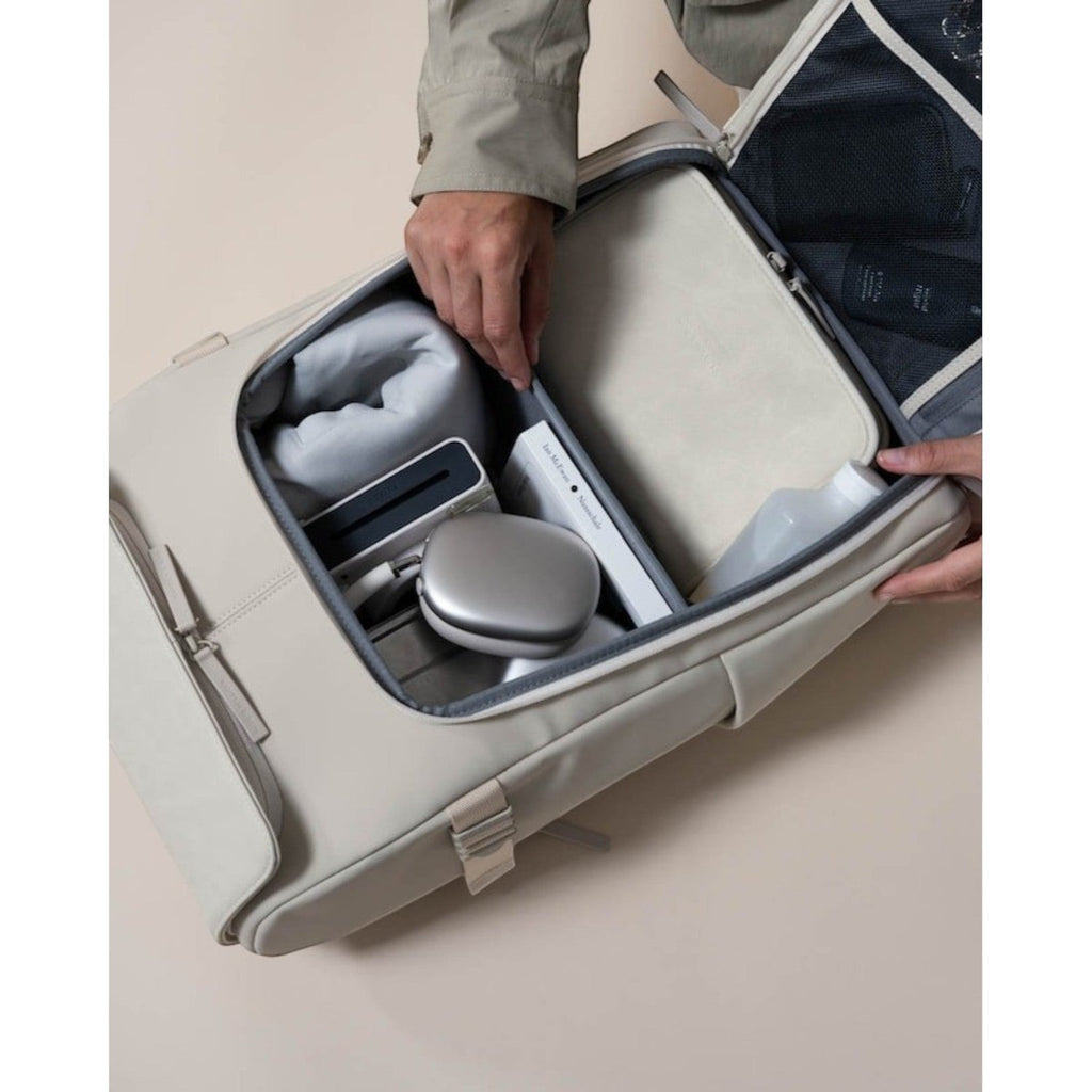 Lieblingstasche Bali Pro beige travel backpack open, showing organized packing with headphones, book, and toiletries.
