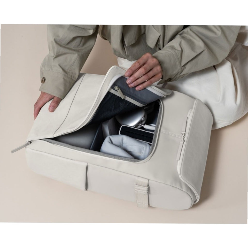 Lieblingstasche Bali Pro light grey backpack with open main compartment showing tech accessories and a person's hands organizing items.