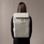 Lieblingstasche Bali Pro light grey vegan leather backpack with flap closure and front pocket, worn by a person.