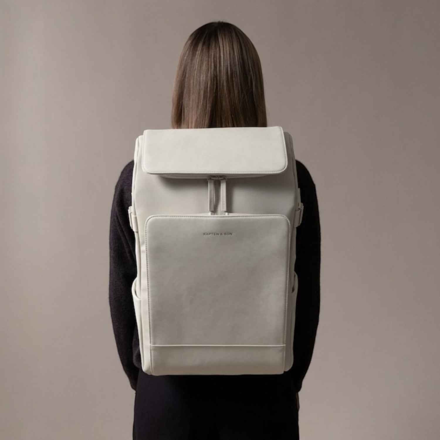 Lieblingstasche Bali Pro light grey vegan leather backpack with flap closure and front pocket, worn by a person.