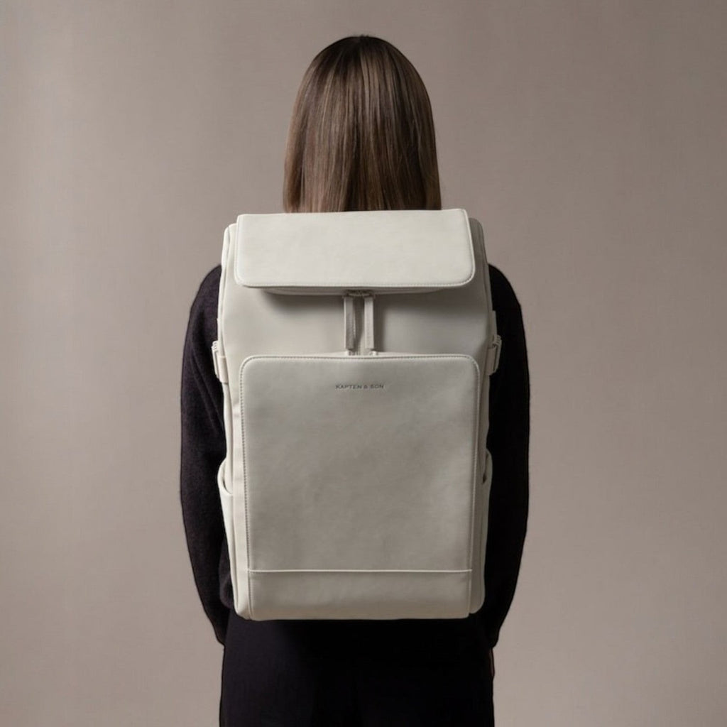 Lieblingstasche Bali Pro light grey vegan leather backpack with flap closure and front pocket, worn by a person.