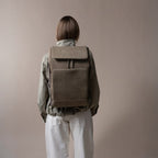 Lieblingstasche Bali Pro taupe faux leather backpack with flap closure and front pocket, worn by a person from behind.