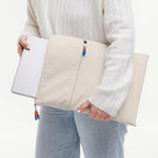 Lieblingstasche Rolltop Lite 2.0 beige laptop sleeve with zipper and colorful pull tabs held by a person
