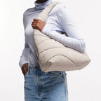 Lieblingstasche beige wavy puffer shoulder bag worn by a smiling woman in a light blue turtleneck