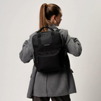 Lieblingstasche Bergen black minimalist backpack with laptop compartment worn by a woman in a grey blazer