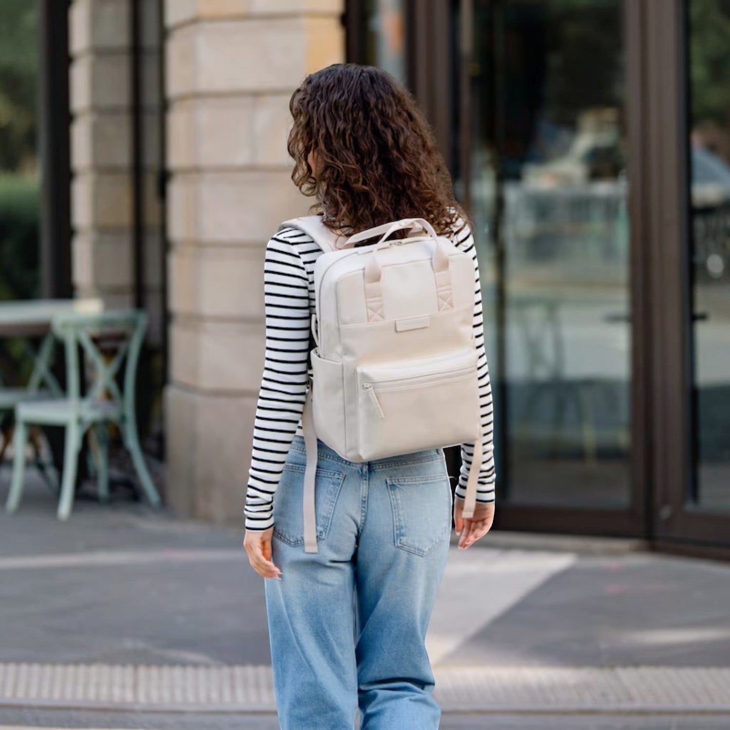 Lieblingstasche Bergen Pro backpack in beige worn by a woman with long curly hair in a city setting.