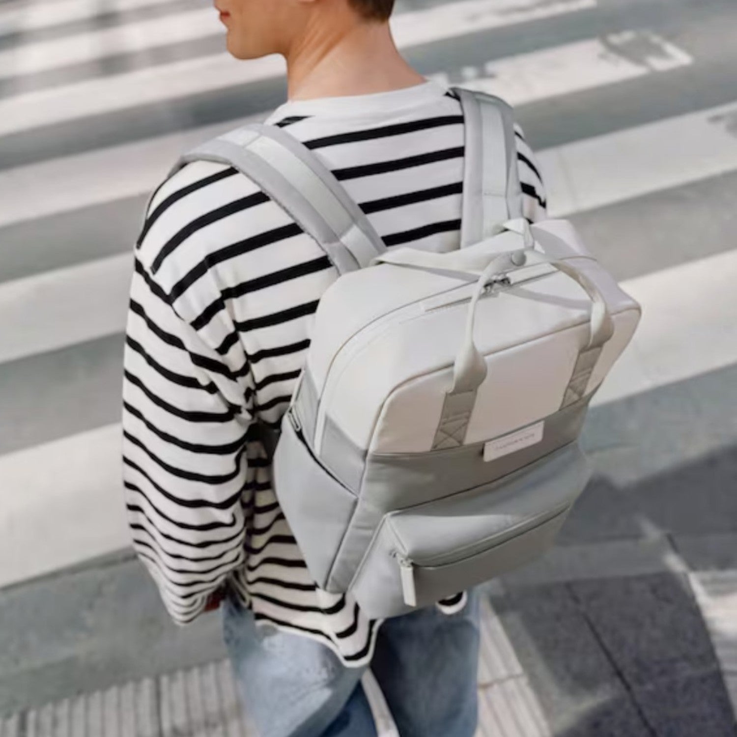 Lieblingstasche Bergen Pro backpack in light grey and white worn by a man in a striped shirt on a city street