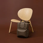 Lieblingstasche Bergen Pro backpack in taupe with padded straps and laptop compartment against a wooden chair
