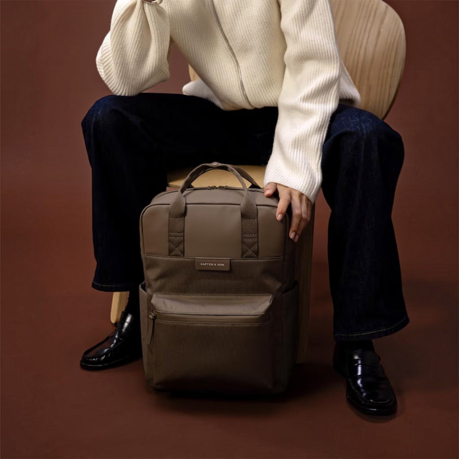 Lieblingstasche Bergen Pro backpack in taupe with padded straps and laptop compartment, shown next to a seated model.