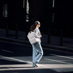 Lieblingstasche Bergen Pro backpack in off-white worn by a woman walking across a city street in casual attire