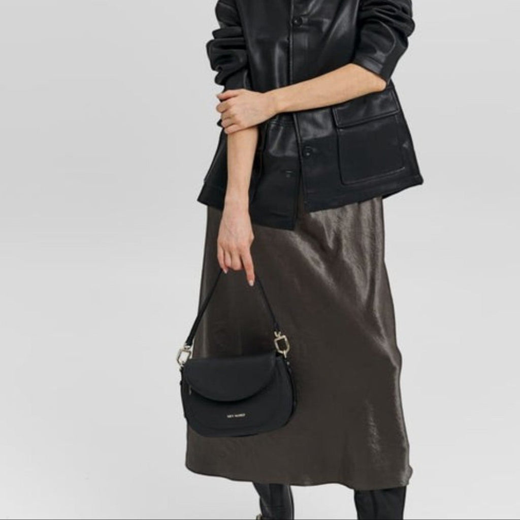 Lieblingstasche Big Sister black leather shoulder bag held by a model wearing a black jacket and metallic skirt