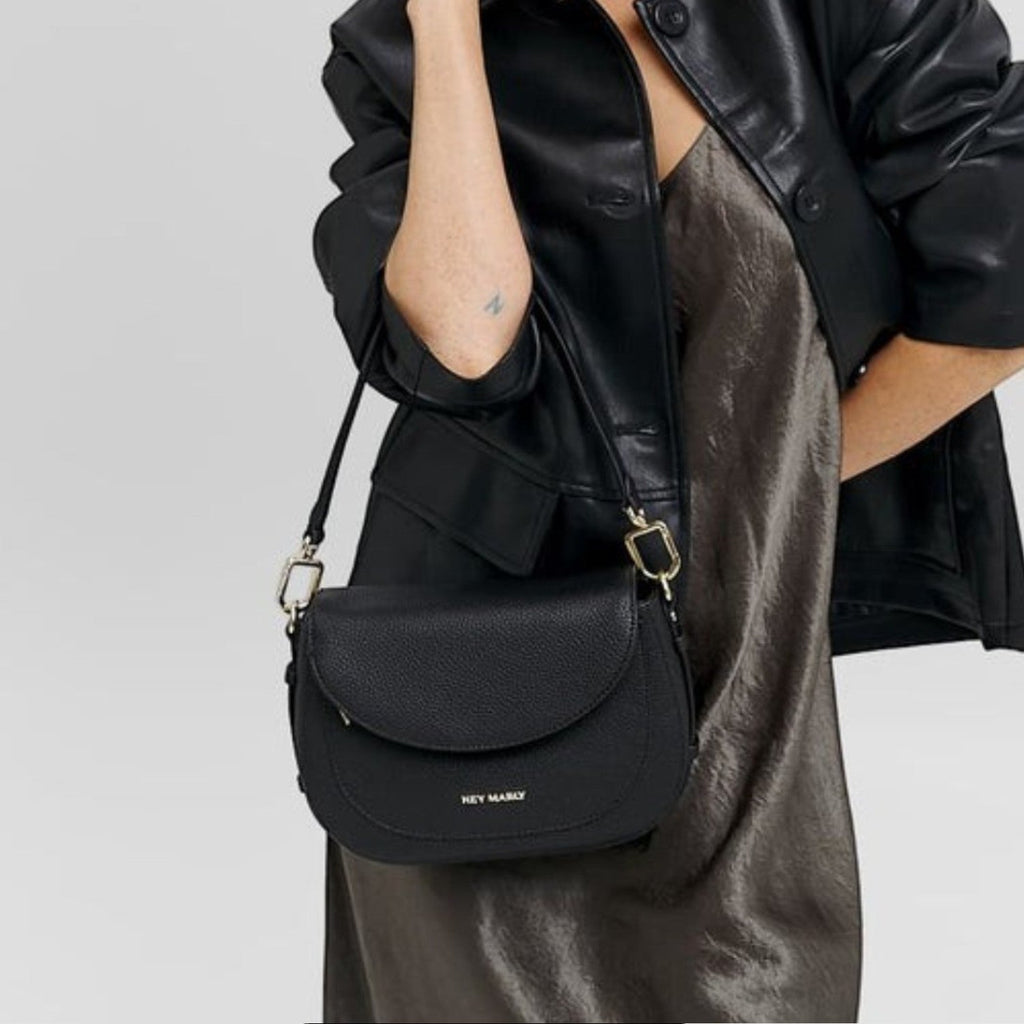 Lieblingstasche Big Sister black pebbled leather crossbody bag worn by a woman in a black jacket and satin dress