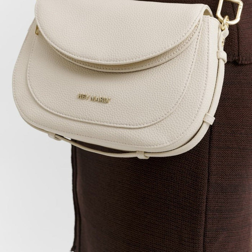 Lieblingstasche Big Sister cream-colored pebbled leather crossbody bag with gold hardware worn over a brown dress