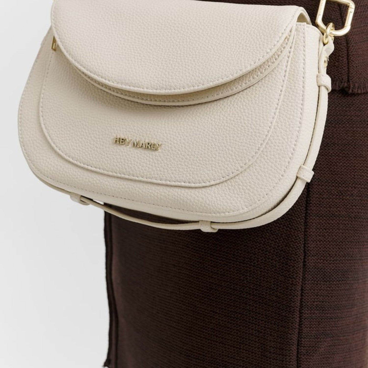 Lieblingstasche Big Sister cream-colored pebbled leather crossbody bag with gold hardware worn over a brown dress