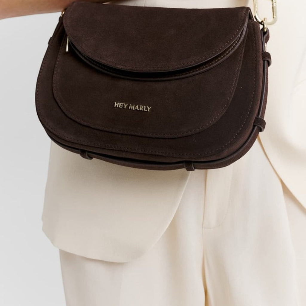 Lieblingstasche Big Sister Suede dark brown crossbody bag with gold hardware worn over a cream blazer
