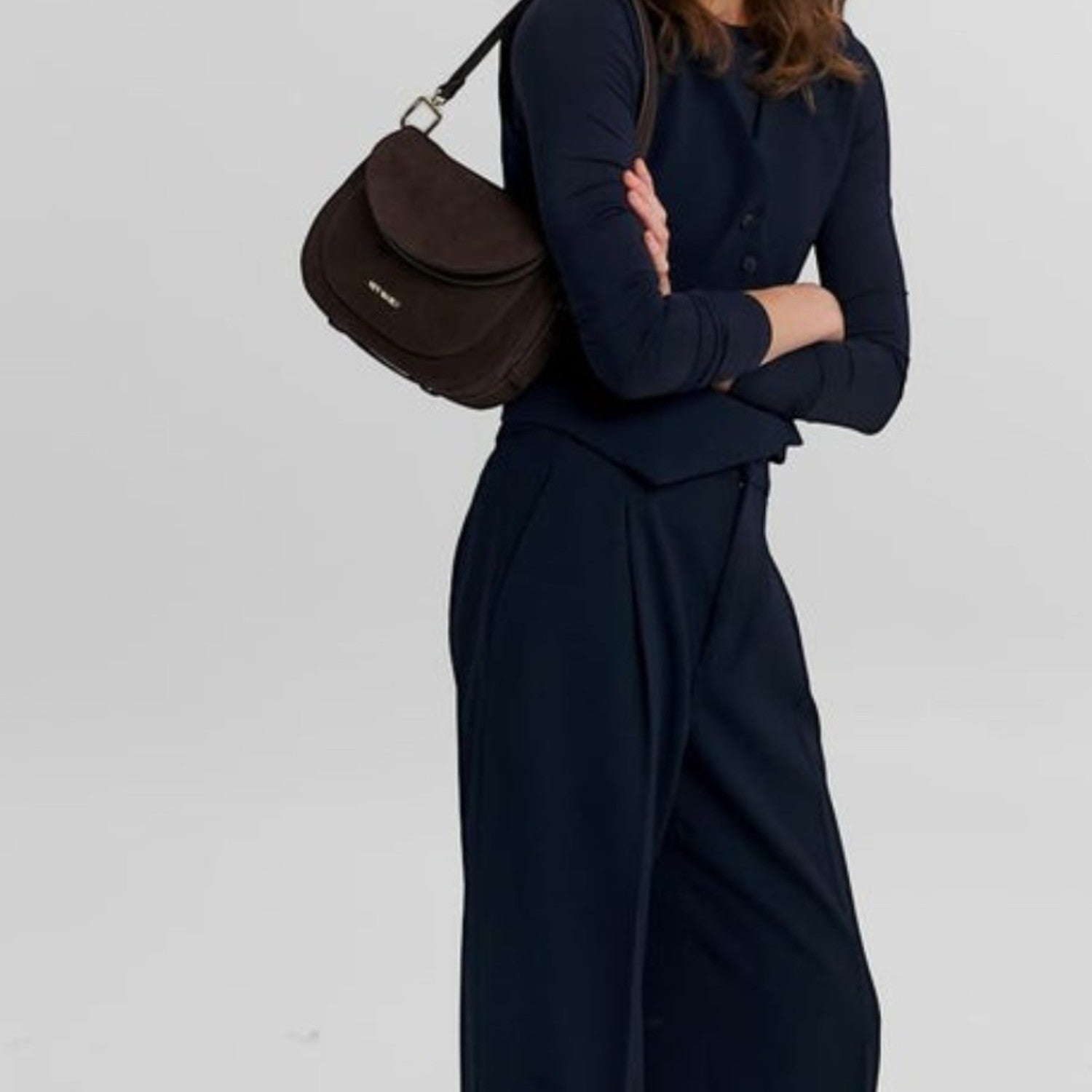 Woman wearing a navy outfit carrying a Lieblingstasche Big Sister Suede dark brown shoulder bag
