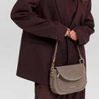 Lieblingstasche Big Sister Suede taupe leather shoulder bag worn by a smiling woman in a dark burgundy suit