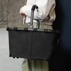 Lieblingstasche black Carrybag shopping basket with a sturdy aluminium handle held by a person in casual clothing