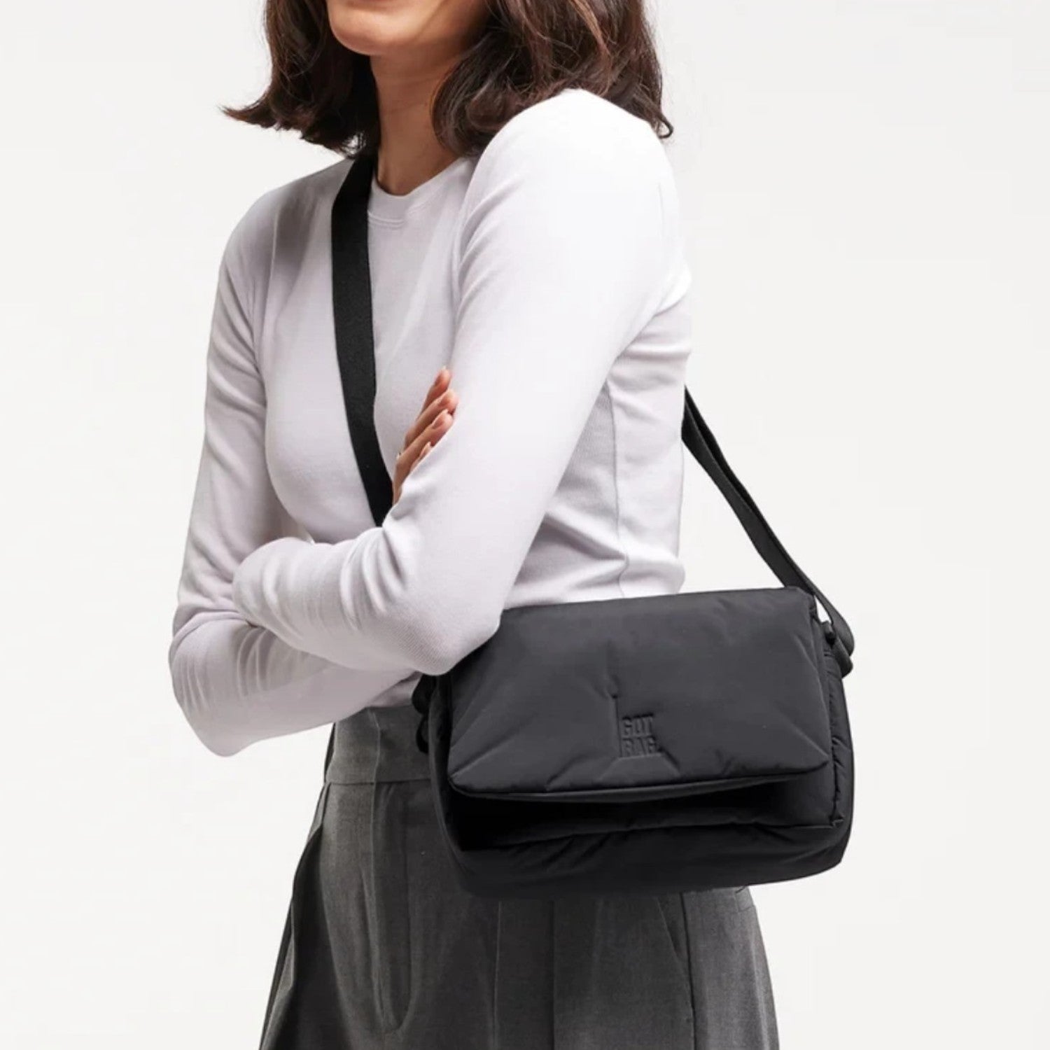 Woman smiling while wearing a black Lieblingstasche Cloud Crossbody Bag made of water-resistant RE:NYNET material.