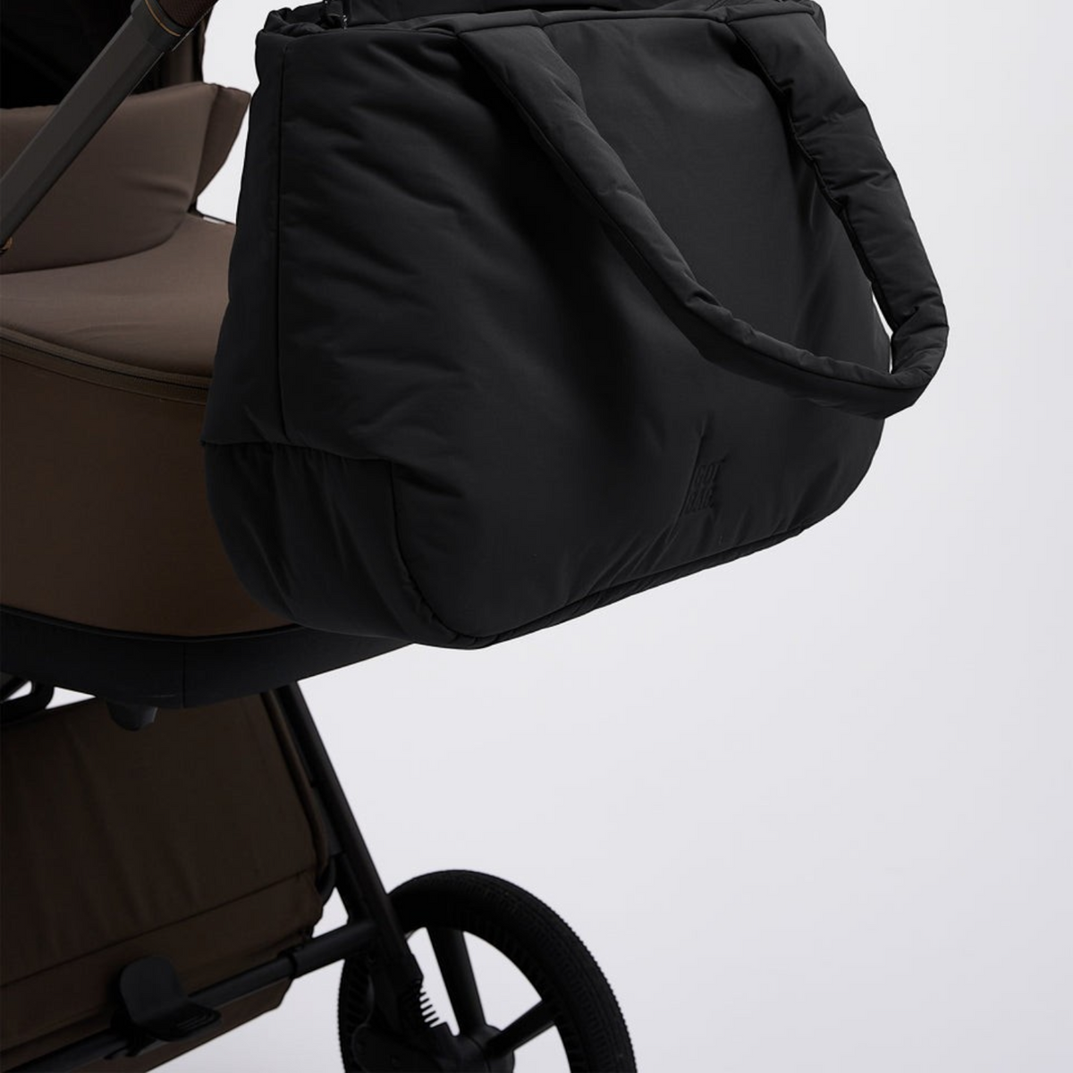 Lieblingstasche Cloud Horizon black padded tote bag hanging from a brown stroller handle