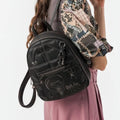 Woman wearing a black Lieblingstasche backpack with quilted stitching and graphic embroidery on her shoulder