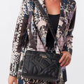 A woman wearing a black Lieblingstasche cross-body bag with quilted geometric patterns and a branded shoulder strap.