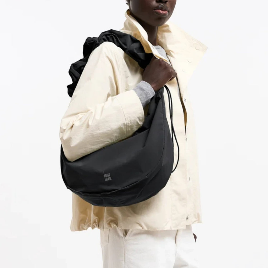 Lieblingstasche Moon Bag Ruffle Large in black, made from recycled fishing nets, worn as a shoulder bag by a model.