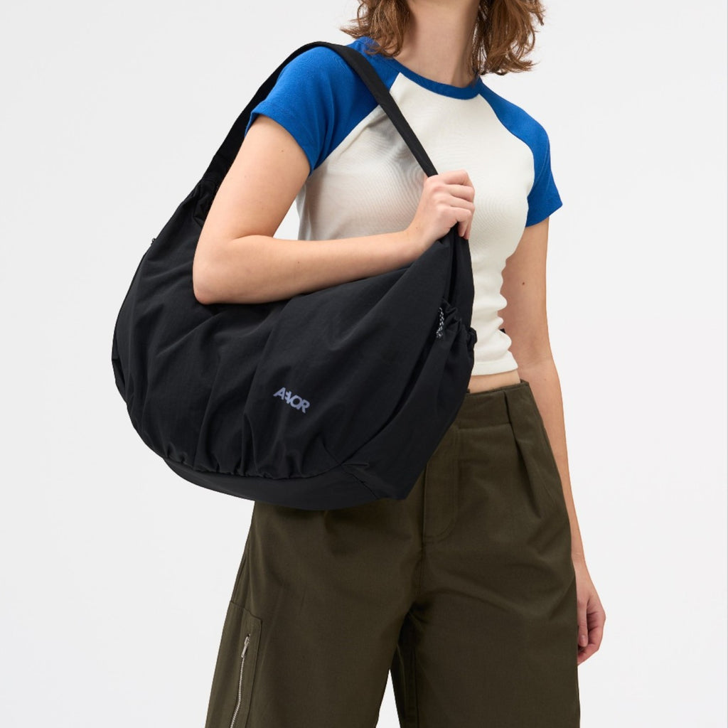 Lieblingstasche black slouchy shoulder bag worn by a woman against a white background