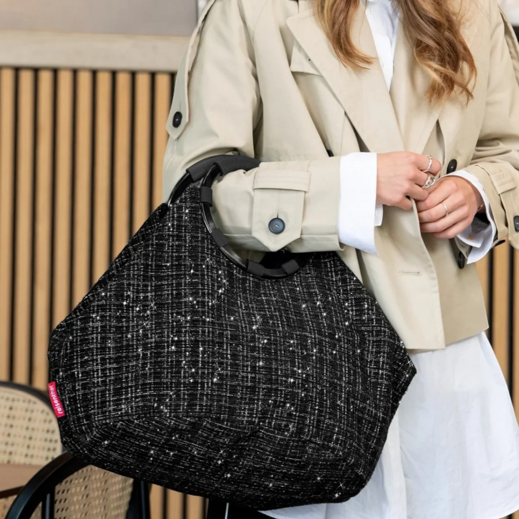 Woman wearing a beige trench coat carrying a black textured Lieblingstasche Loopbag Hobo with a circular handle
