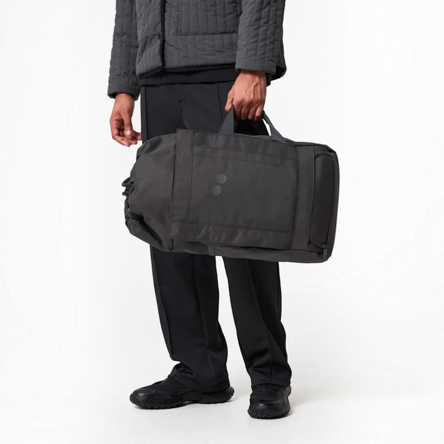Lieblingstasche Blok Medium charcoal grey duffel bag held by a person wearing matching dark casual clothing