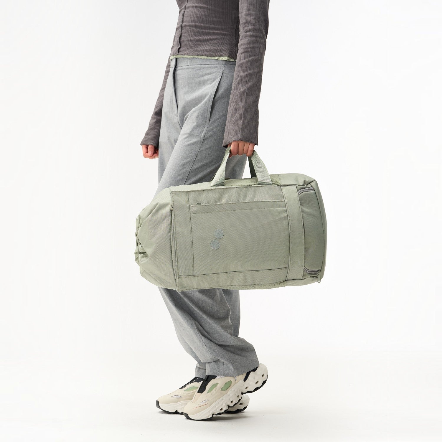 Lieblingstasche Blok Medium sage green travel bag with side pockets and top handles held by a person