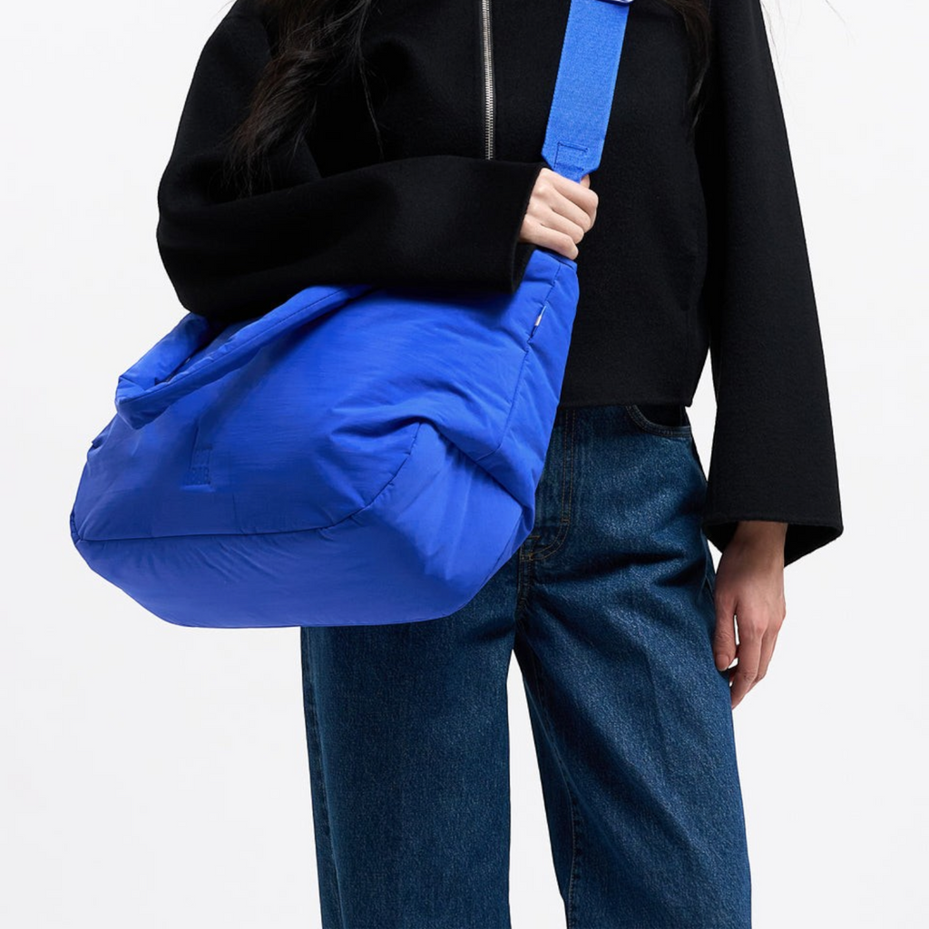 Model wearing a bright blue Lieblingstasche Cloud Horizon tote bag with an adjustable crossbody strap