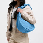 Lieblingstasche blue large moon bag with ruffle detail, worn by a woman.