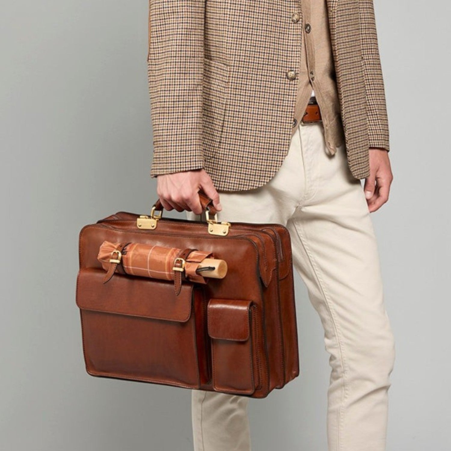 Lieblingstasche brown leather briefcase, 42 cm, with brass hardware and front pockets. Model wears a tweed blazer.