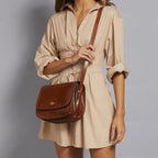 Lieblingstasche brown leather crossbody bag with multiple compartments and gold-tone clasp, worn by a model in a beige dress.