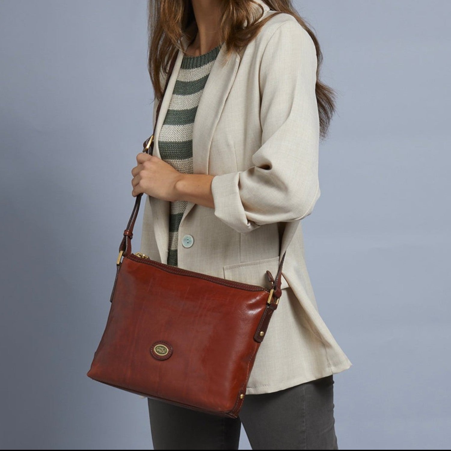 Lieblingstasche brown leather crossbody bag with zipper closure and gold hardware, worn by a model.