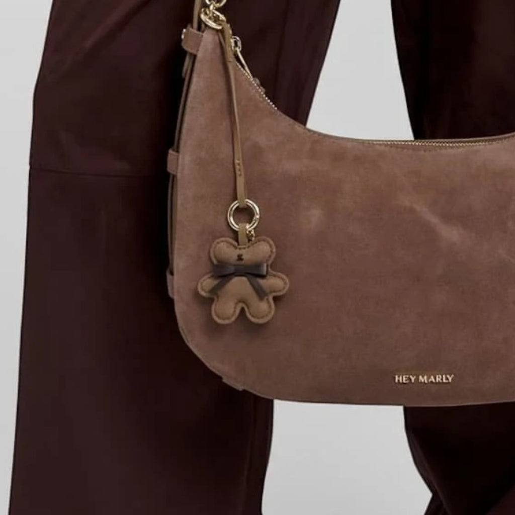 Lieblingstasche Teddy Charm brown suede hobo bag with a cute bear keychain held by a person in a dark suit