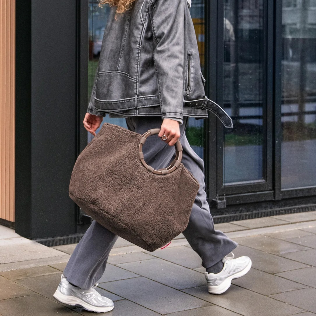 Lieblingstasche Loopbag Hobo in brown teddy fleece with a circular wooden handle carried by a woman in grey outfit