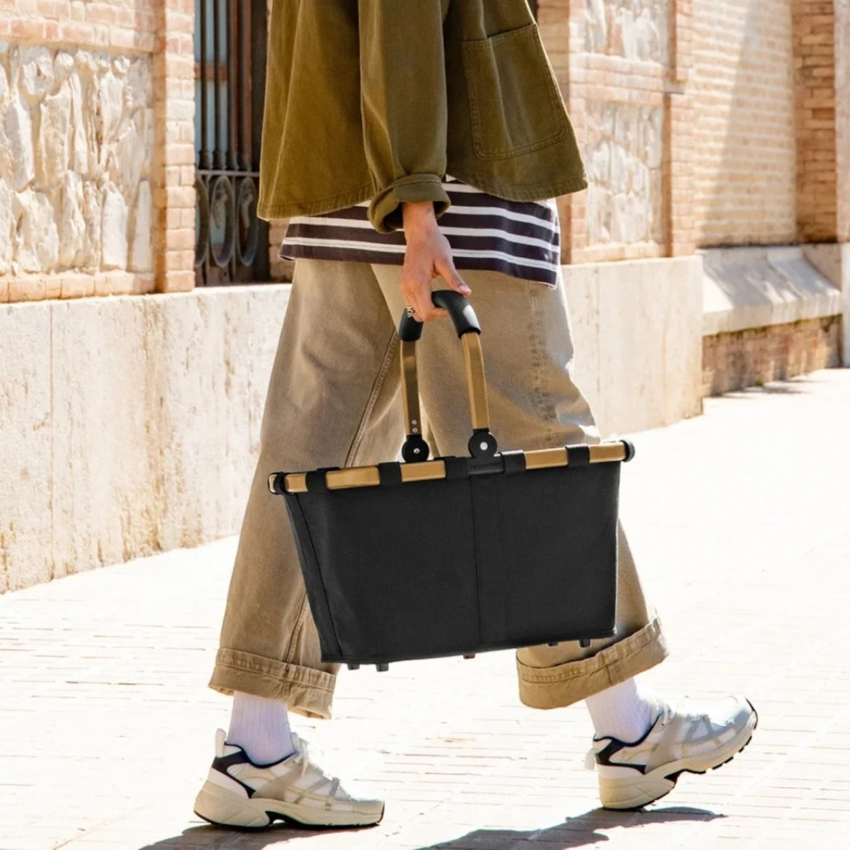 Lieblingstasche Carrybag in black with a sturdy aluminium handle being carried by a woman on a sunny city street