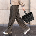 Lieblingstasche Carrybag XS black woven basket with handle, carried by a woman walking outdoors.