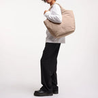 Lieblingstasche Cloud Tote Bag in beige, made from water-resistant RE:NYNET material, worn over the shoulder by a model
