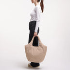 Lieblingstasche Cloud Tote Bag in beige, made from water-resistant RE:NYNET material, held by a woman in profile.