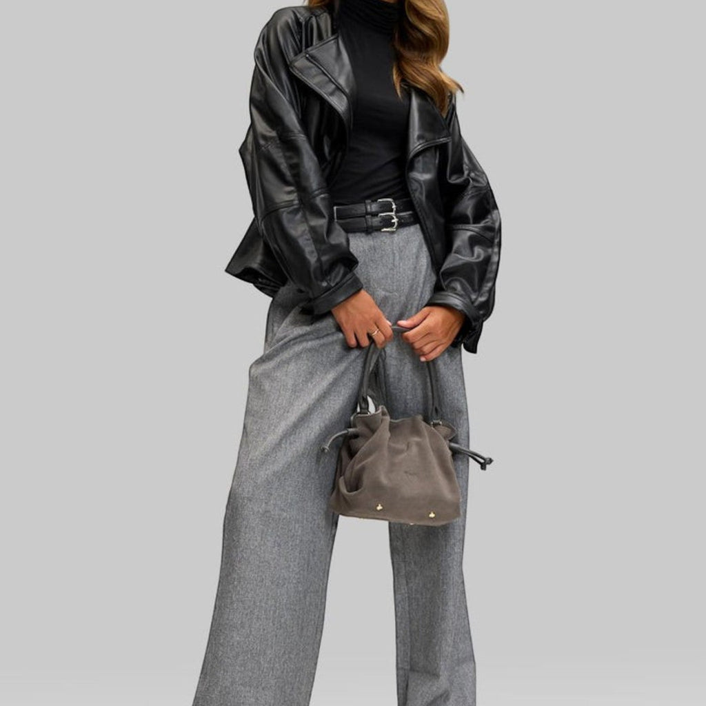 Lieblingstasche Cool Companion Suede S grey suede handbag with drawstring closure held by a woman in a black jacket