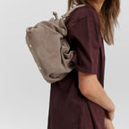 Lieblingstasche Cool Companion Suede S taupe suede leather backpack worn by a woman in a dark burgundy outfit