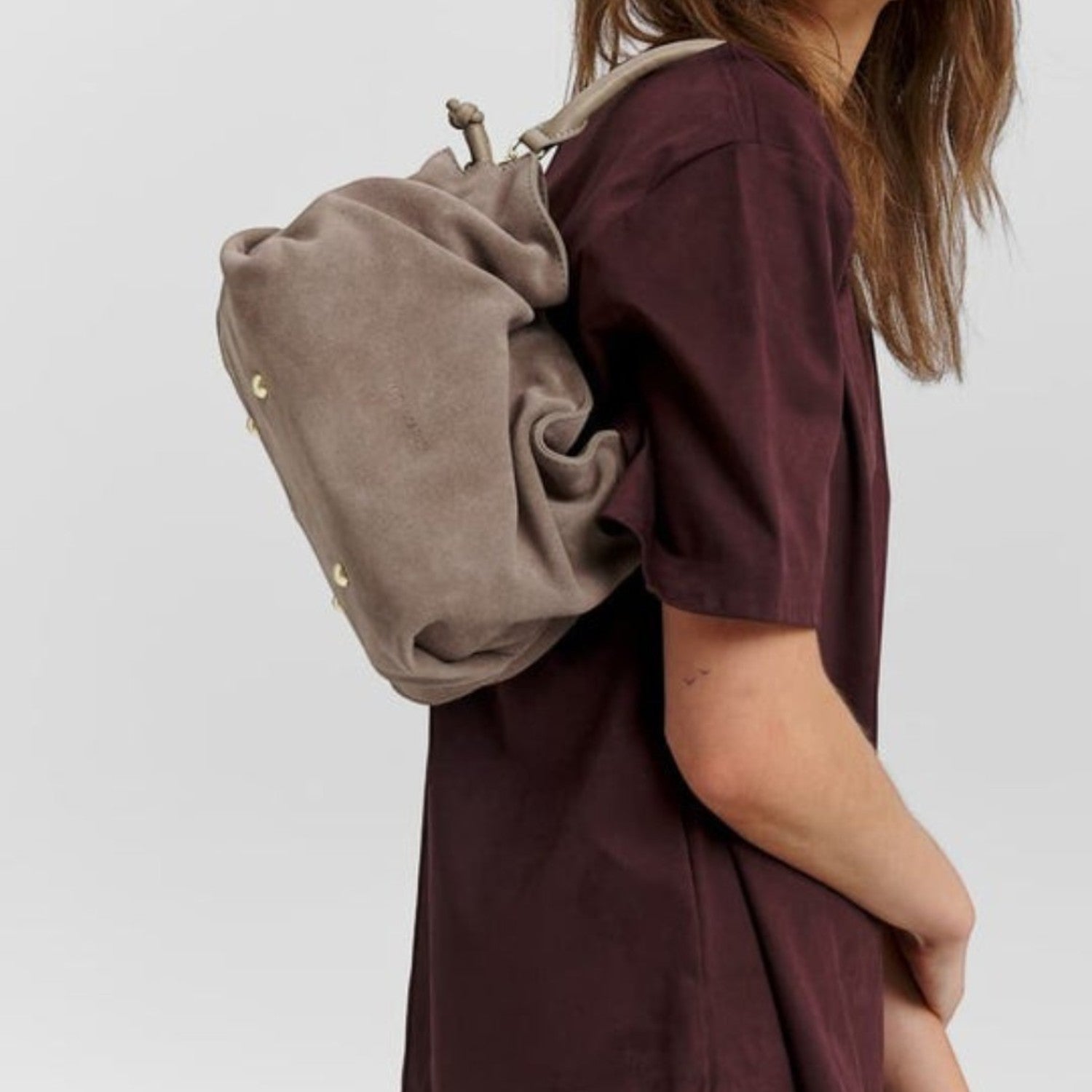 Lieblingstasche Cool Companion Suede S taupe suede leather backpack worn by a woman in a dark burgundy outfit